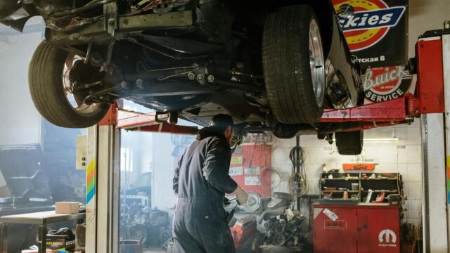 Mechanic inspecting drivetrain components during Heavy Duty Transmission repair while working under a lifted truck